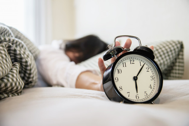 sleepy-woman-reaching-holding-alarm-clock_1150-6975